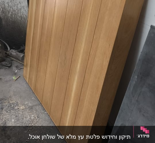 לוח עץ מונח על רצפה ליד קיר לבן